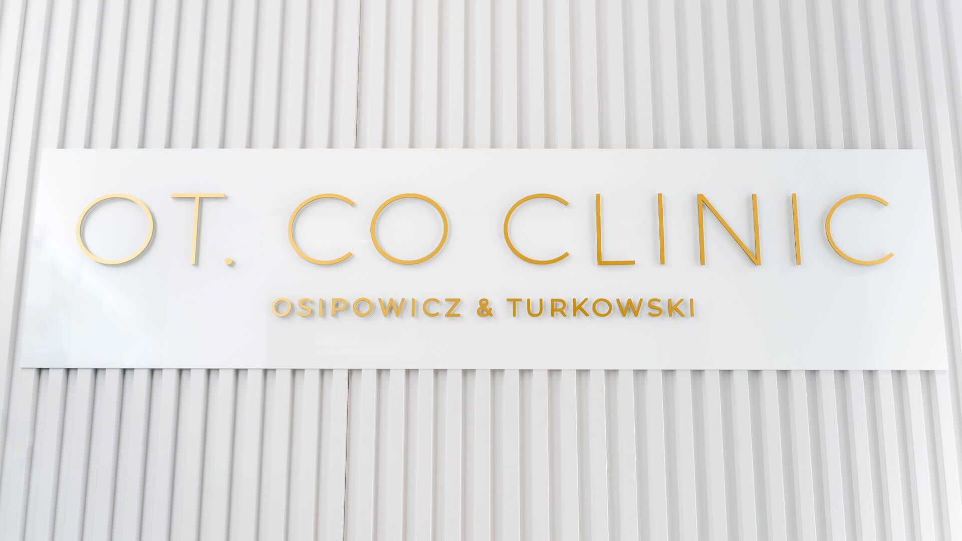 Muurletters OT.CO Kliniek - Gouden prismatische letters op de muur in de ontvangstruimte van OT.CO Clinic