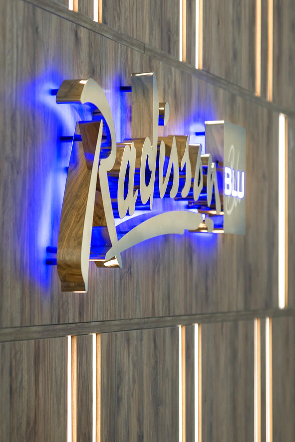 radisson sopot blu hotel - radisson-blauwe-letters-van-zilver-plaat-gouden-letters-behind-receptie-in-hotel-op-een-houten-muur-licht-van-behind-blauw-sopot-logo-company-exclusief-glamour